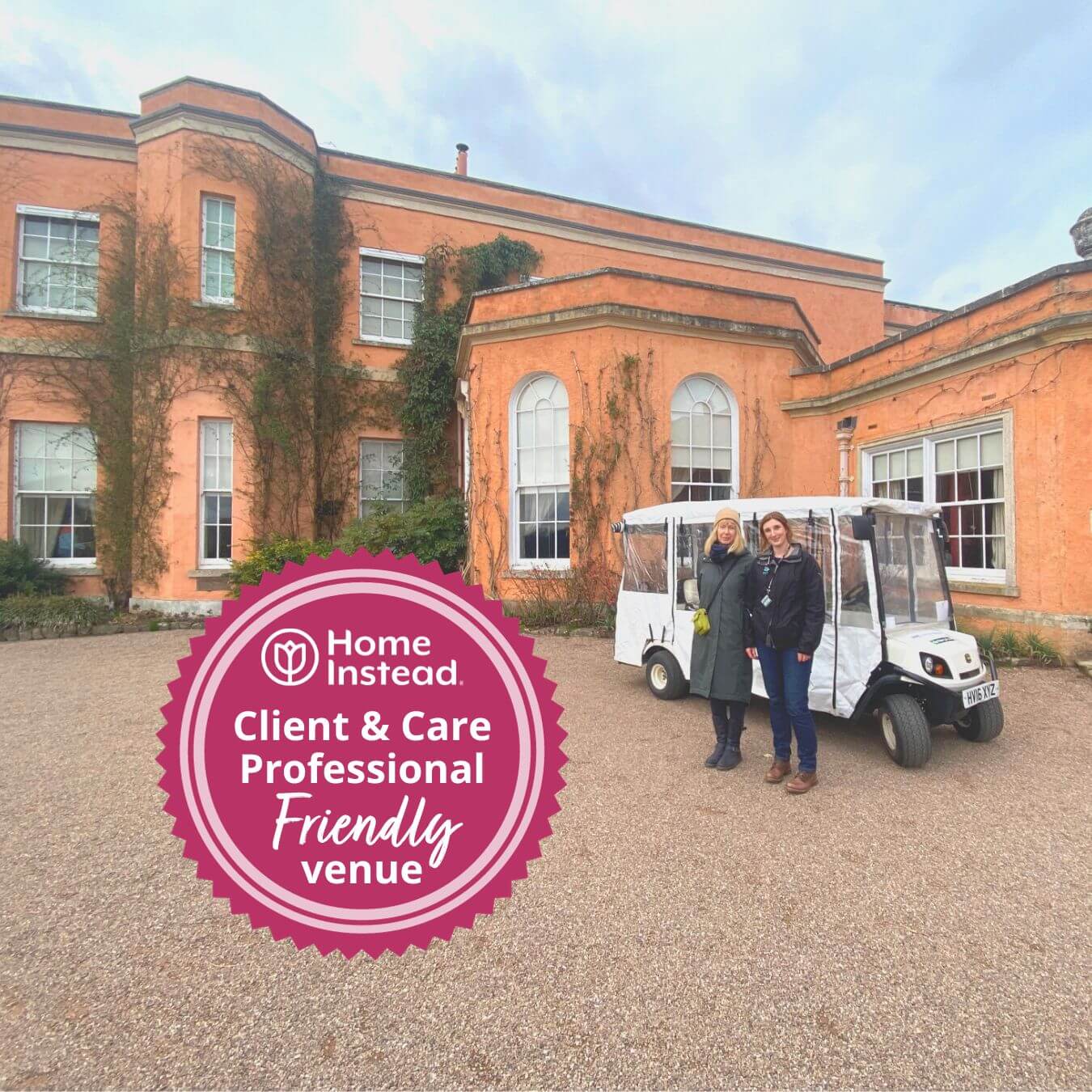 Two people stand beside a golf cart in front of a large historic building with a "Friendly Venue" badge in the foreground. - Home Instead