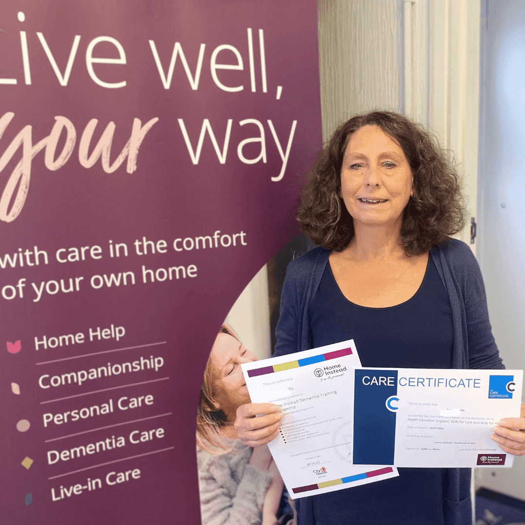 Woman standing with two certificates in hand, smiling beside a banner that says "Live well, your way" and offers various care services. - Home Instead