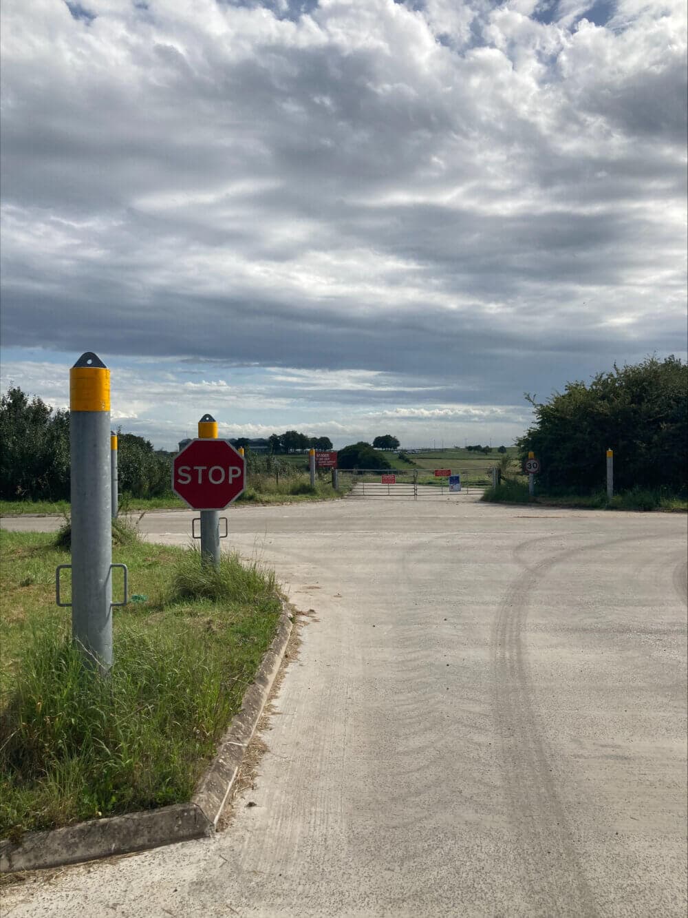 A rural road with a stop sign, surrounded by fields and a cloudy sky above. - Home Instead