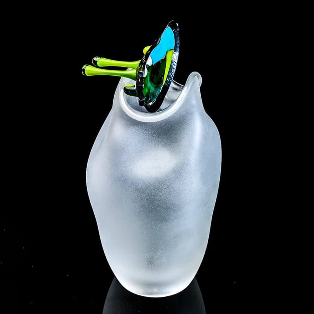 A frosted vase with a colorful, abstract glass piece inserted into its opening against a black background. - Home Instead