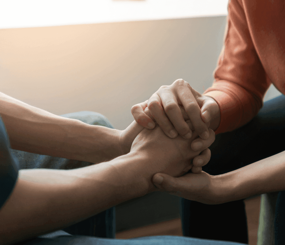 Two people holding hands in a comforting and supportive gesture. - Home Instead