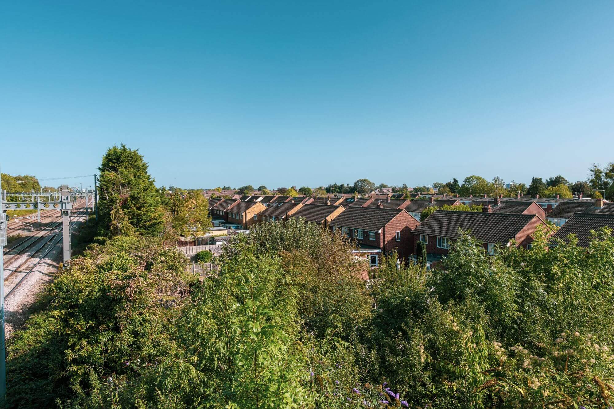 Aerial view of a suburban neighborhood with rows of houses and trees on a clear day. - Home Instead