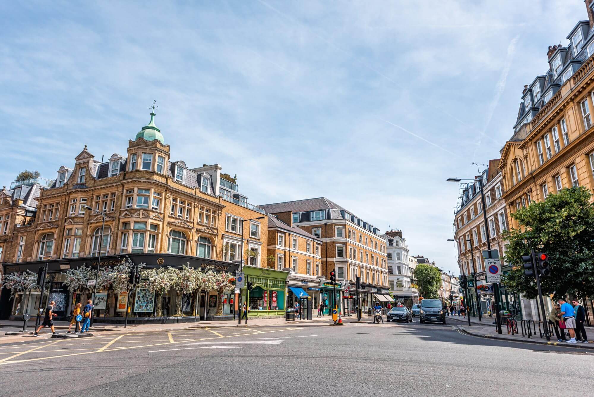 Busy street intersection lined with Victorian-era buildings under a blue sky. Pedestrians crossing and cars waiting. - Home Instead Poole