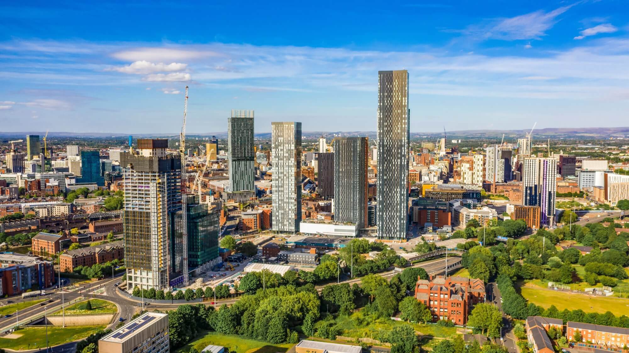 Aerial view of a modern cityscape with tall skyscrapers, surrounding greenery, and a clear blue sky. - Home Instead