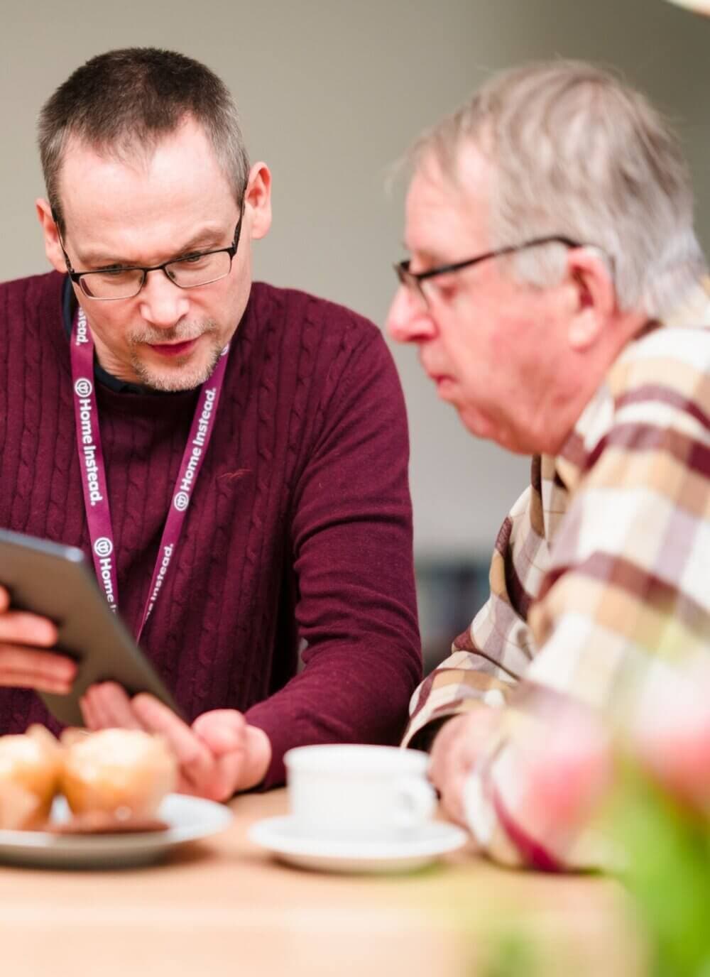Home Instead Bournemouth & Christchurch Care Professional with client using tablet