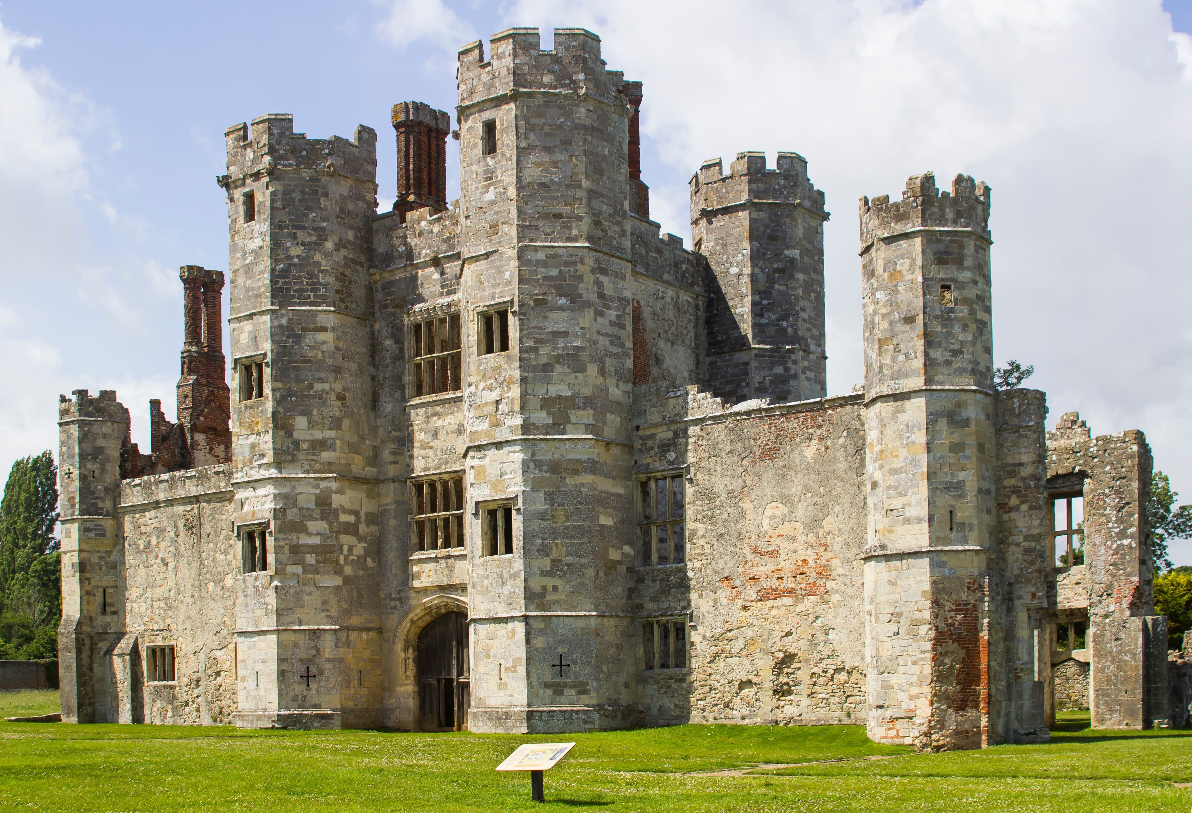 A historic stone castle with multiple towers, surrounded by green grass under a partly cloudy sky. - Home Instead