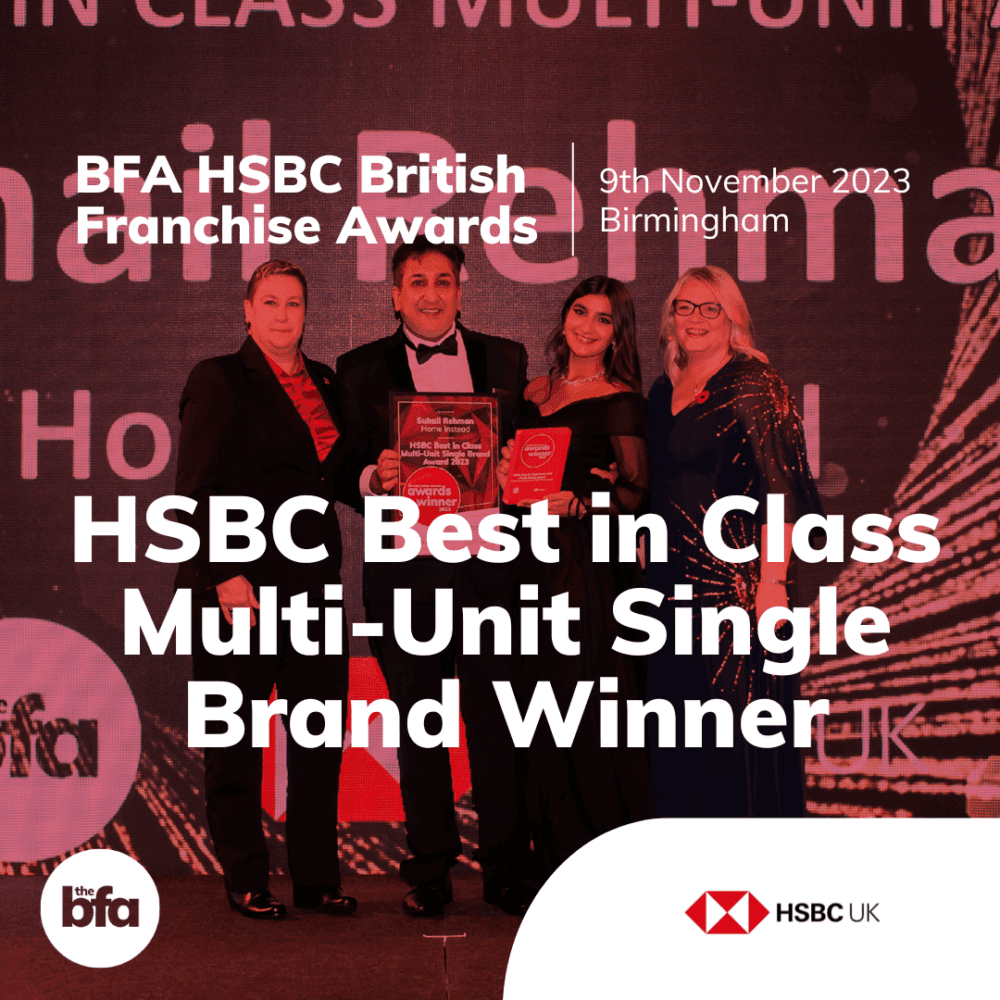 Four people stand together on a stage holding an award. Text reads "HSBC Best in Class Multi-Unit Single Brand Winner". - Home Instead