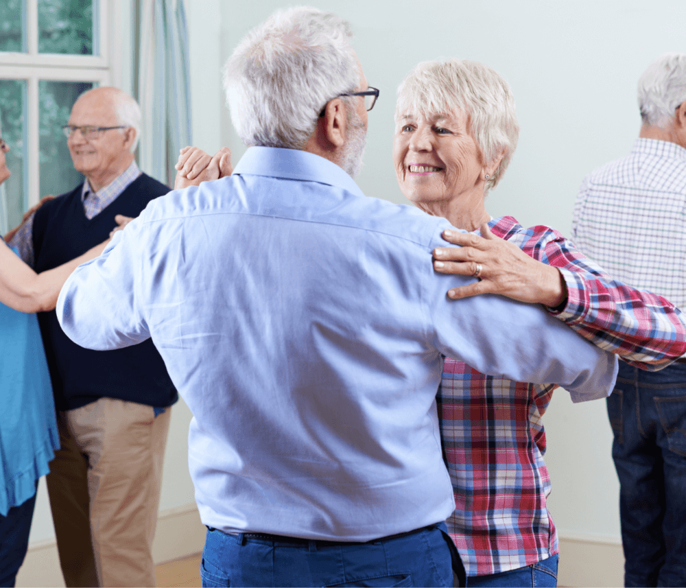 Elderly couples dancing together in a brightly lit room, enjoying themselves. - Home Instead