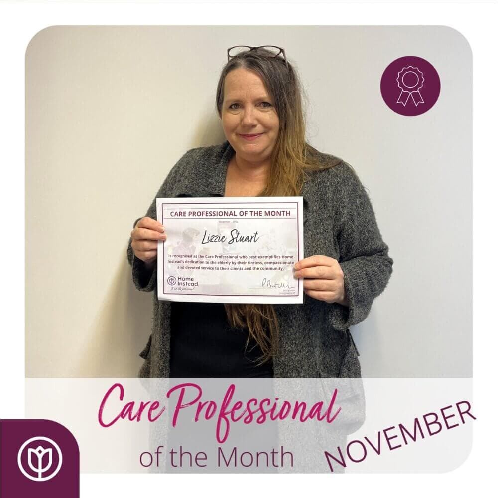 A woman holding a "Care Professional of the Month" certificate for November with text "Eliza Stuart" in the center. - Home Instead