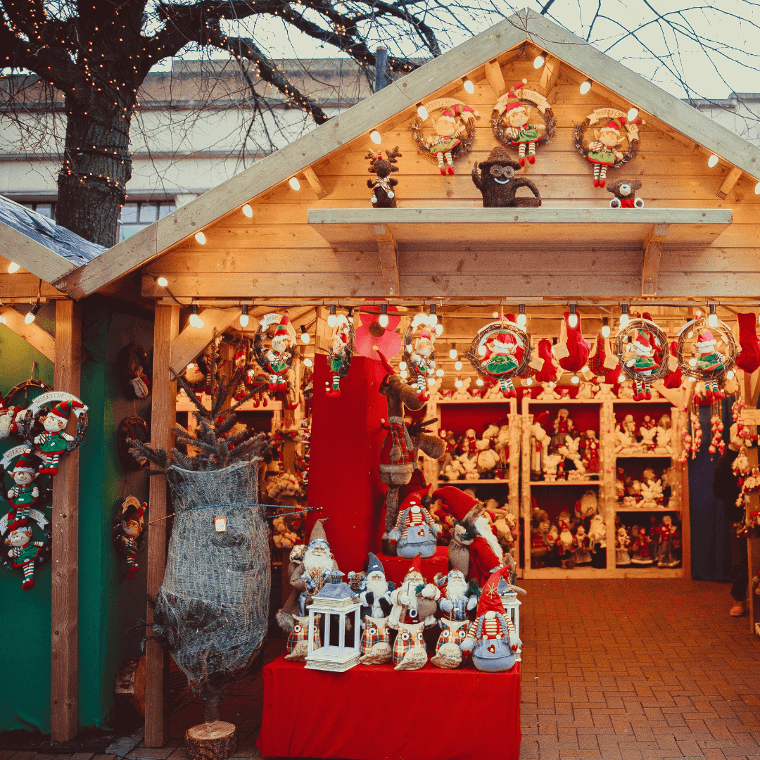 A festive Christmas market stall adorned with lights, wreaths, and various holiday decorations and figurines. - Home Instead