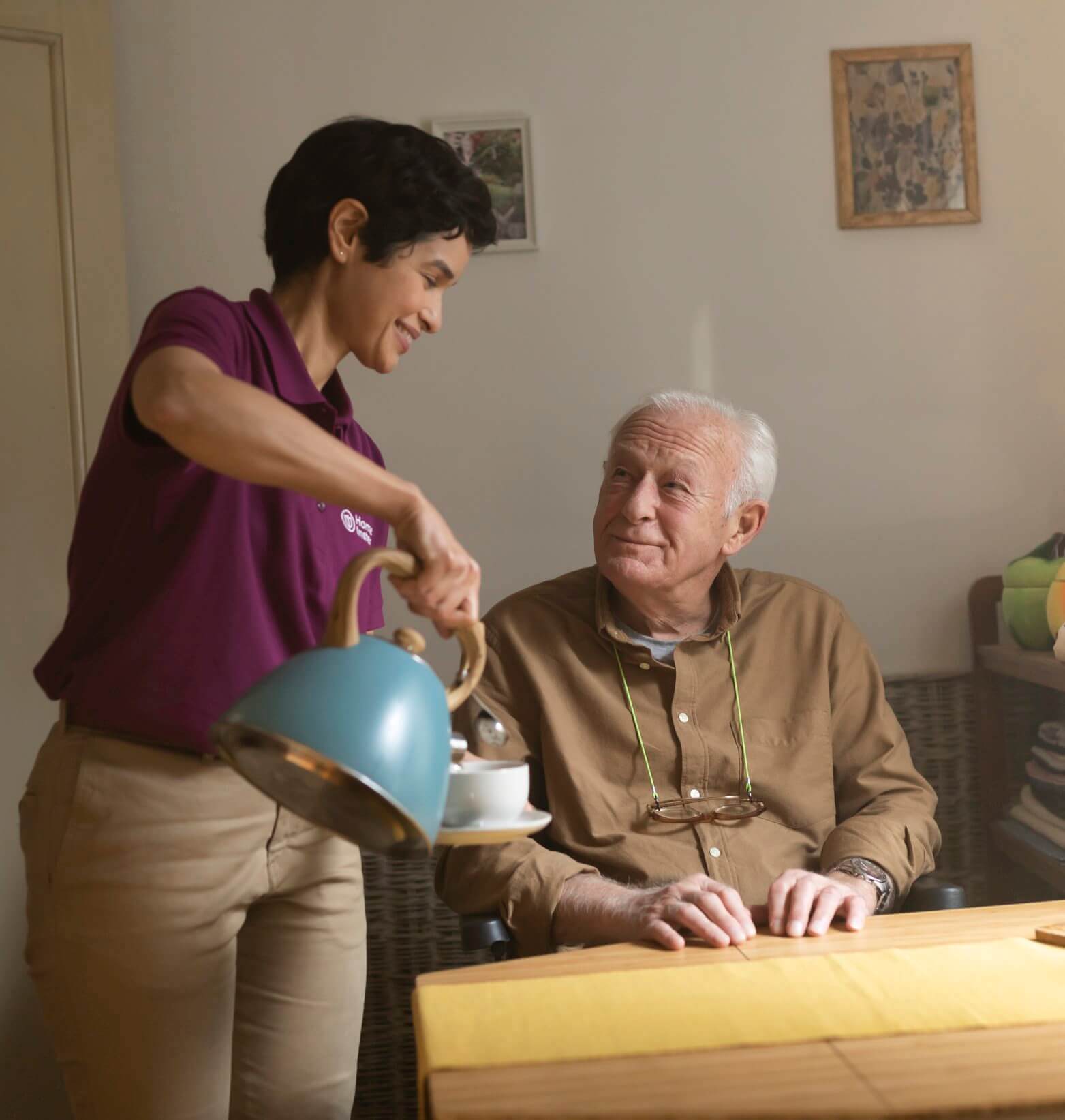 Care Professional pouring client a cup of tea for a elderly client who is smiling. - Home Instead