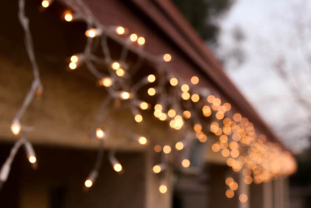 Blurred image of string lights hanging from a roof edge, creating a warm, festive ambiance. - Home Instead