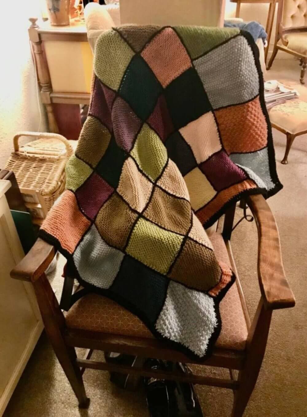 A colorful, patchwork quilt draped over a wooden chair in a cozy room. - Home Instead