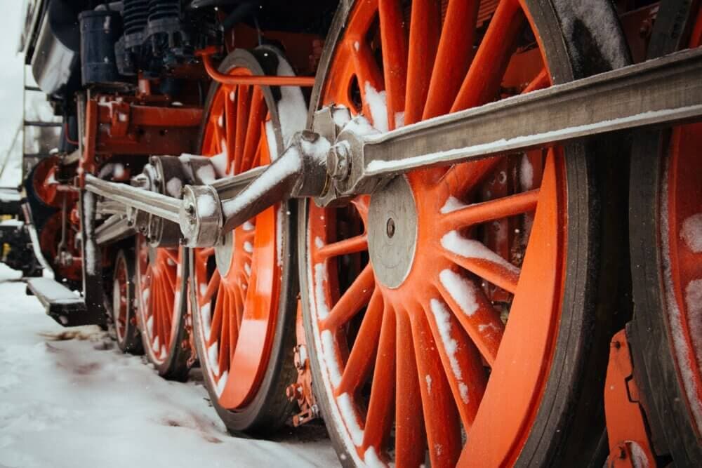 Close-up of red steam train wheels with some snow on them. - Home Instead