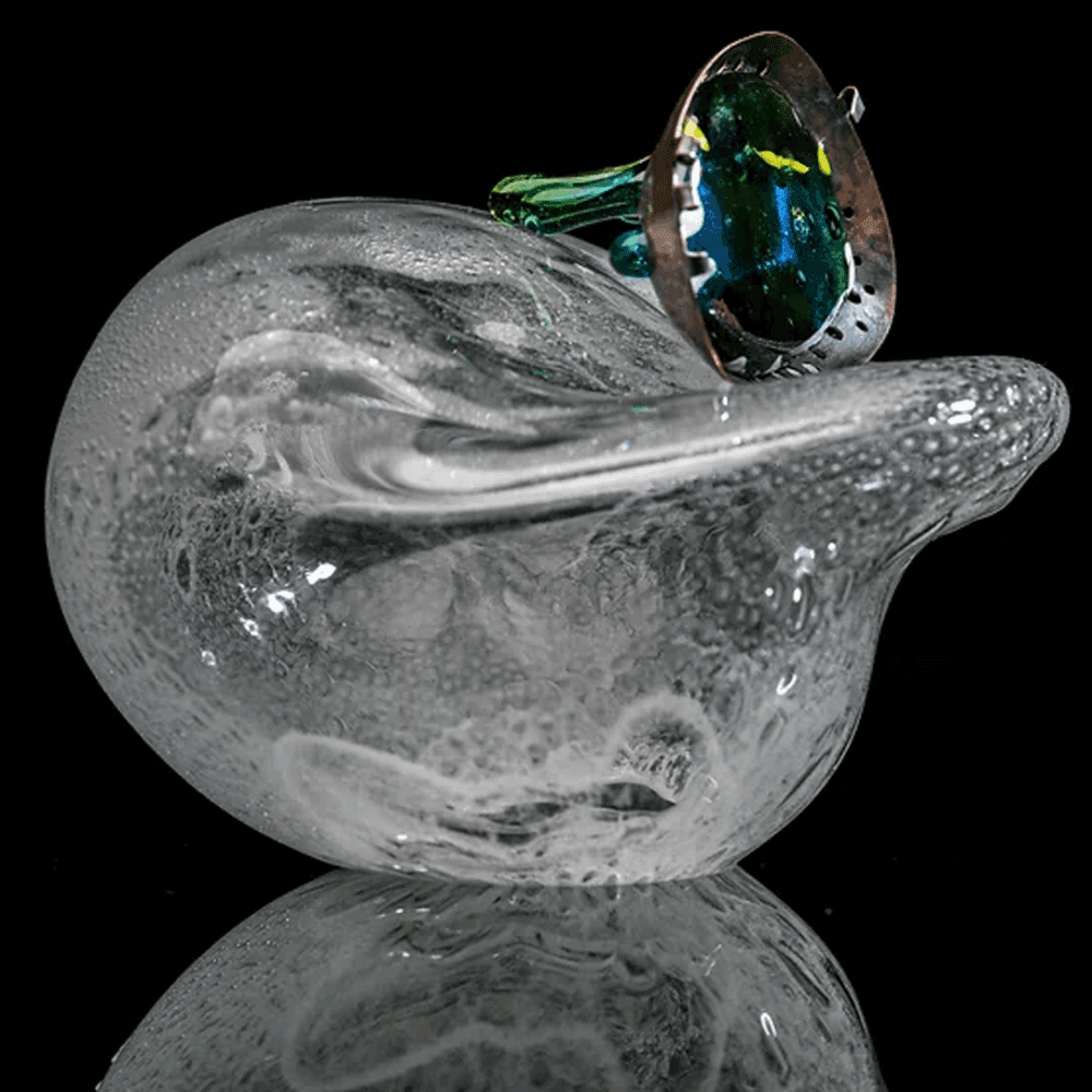 A clear glass duck sculpture with a colorful, intricate top hat, reflecting on a black surface. - Home Instead