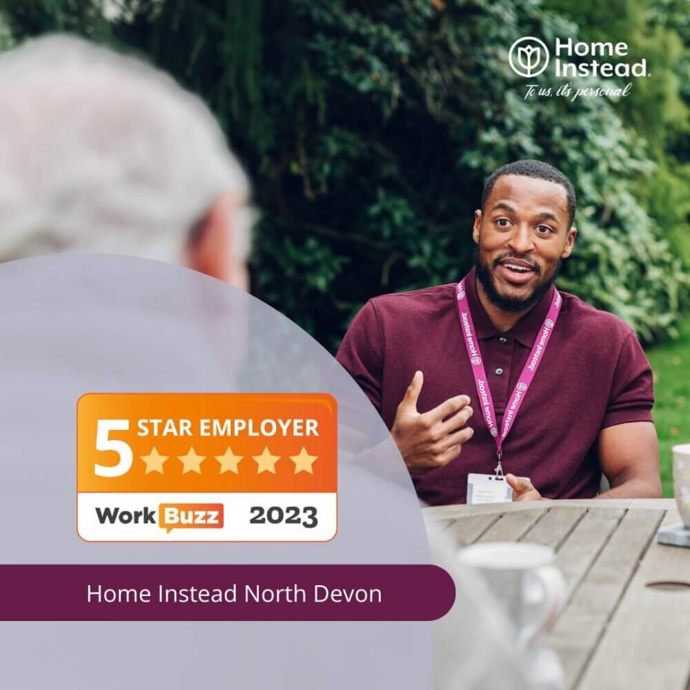 Two people having a conversation outdoors, one wearing a maroon shirt. Text: "Home Instead North Devon, 5 Star Employer WorkBuzz 2023. - Home Instead