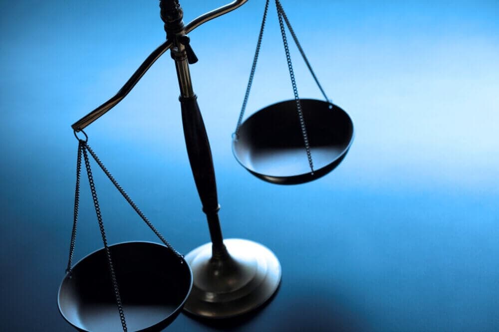 A balance scale with empty black pans on both sides against a blue background. - Home Instead