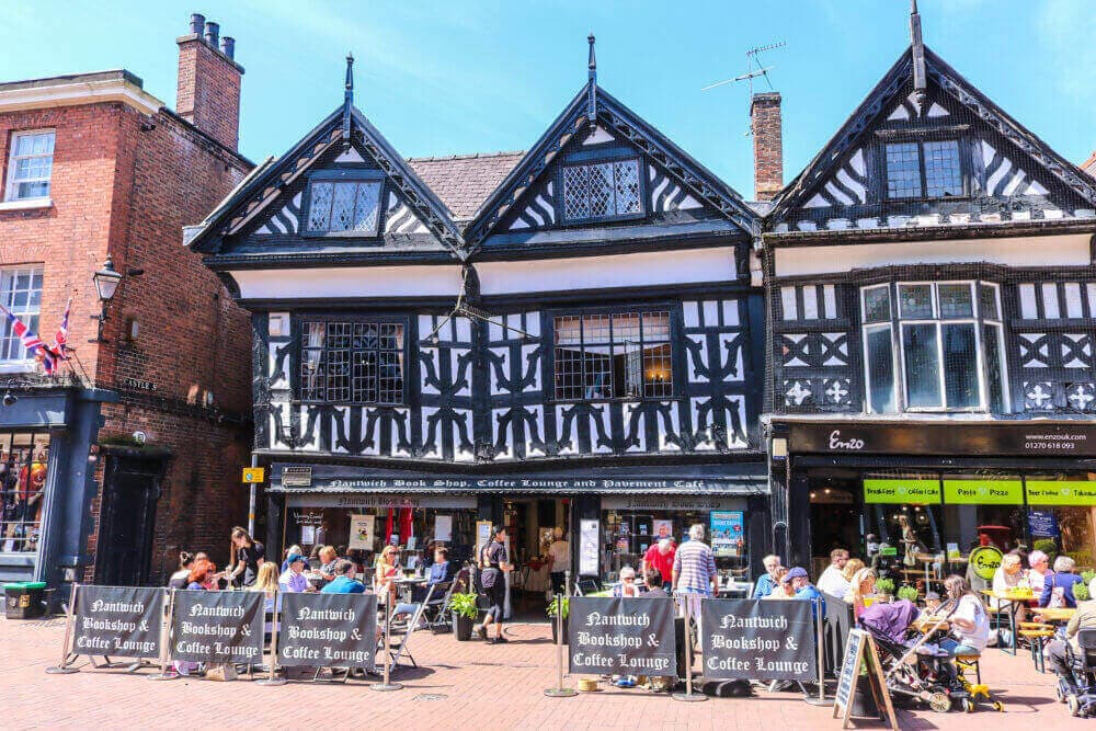 Tudor-style bookshop and coffee lounge with people seated outside on a sunny day in a quaint town. - Home Instead