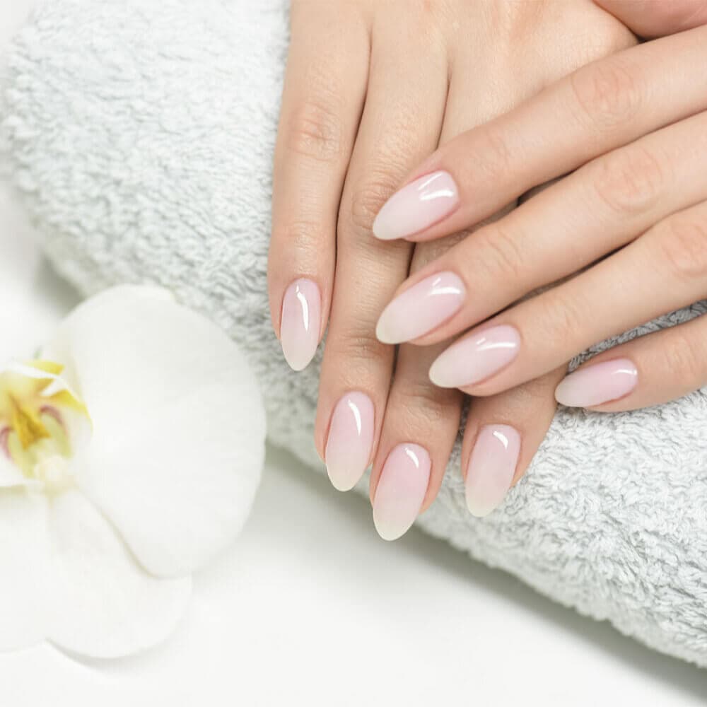 A woman's hands with pink and white manicures on a towel.