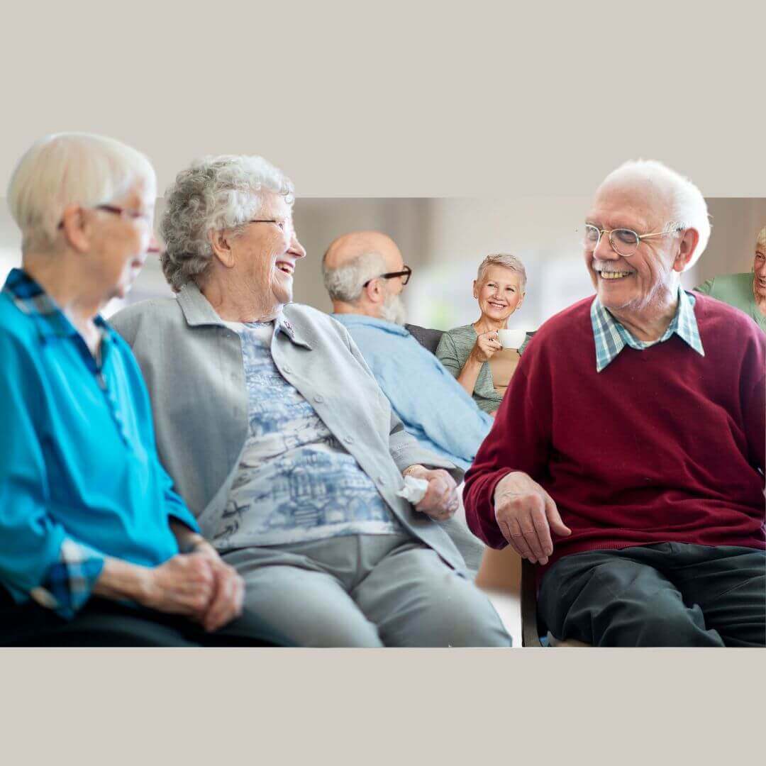 A group of elderly people and a young child are smiling and talking together, enjoying each other's company. - Home Instead
