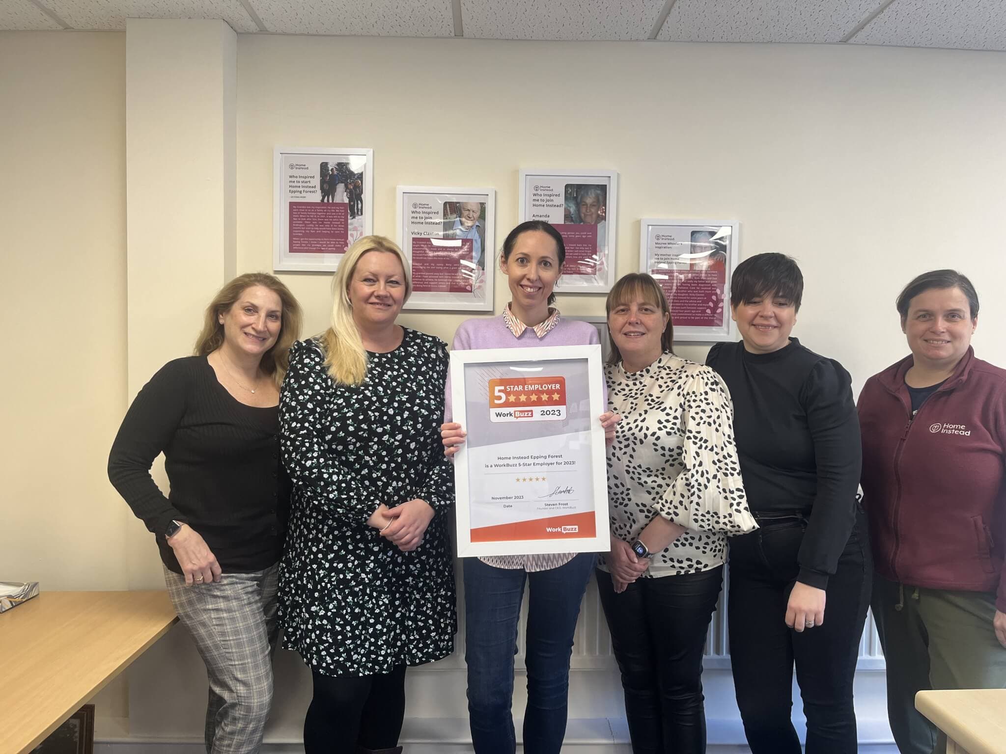 Six people standing together, with one person holding a "5 Star Rated Office March 2023" certificate, smiling. - Home Instead