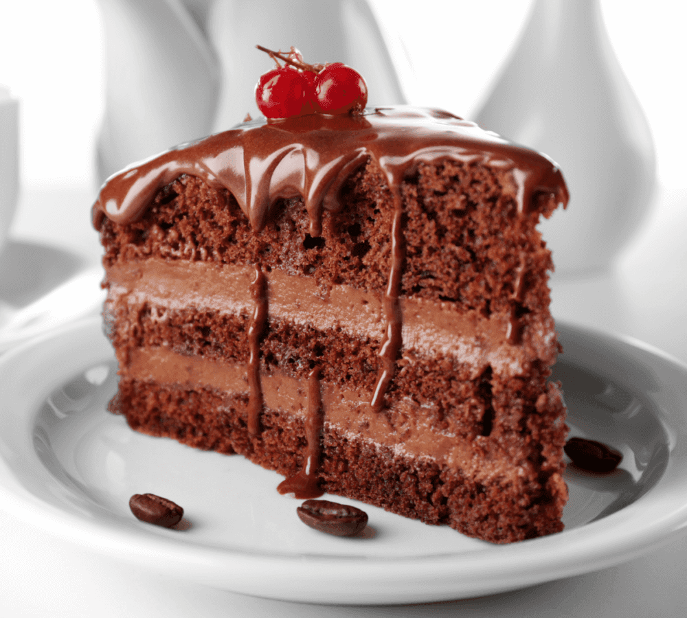 A slice of chocolate cake with a cherry topping on a white plate, decorated with three coffee beans. - Home Instead
