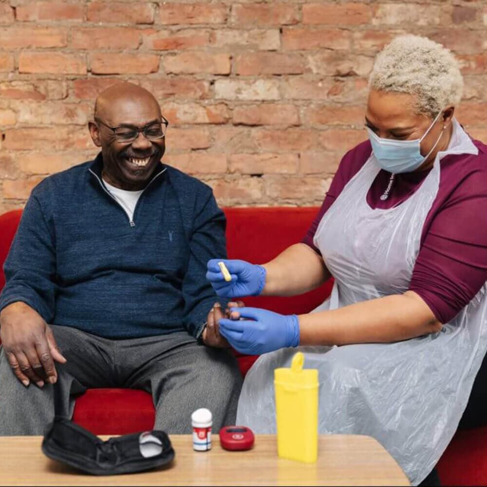 A home instead care professional undertaking supporting a client with blood testing for his diabetes care.