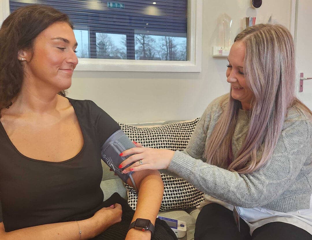 A care professional measuring a lady's blood pressure as part of a healthcare at home service.
