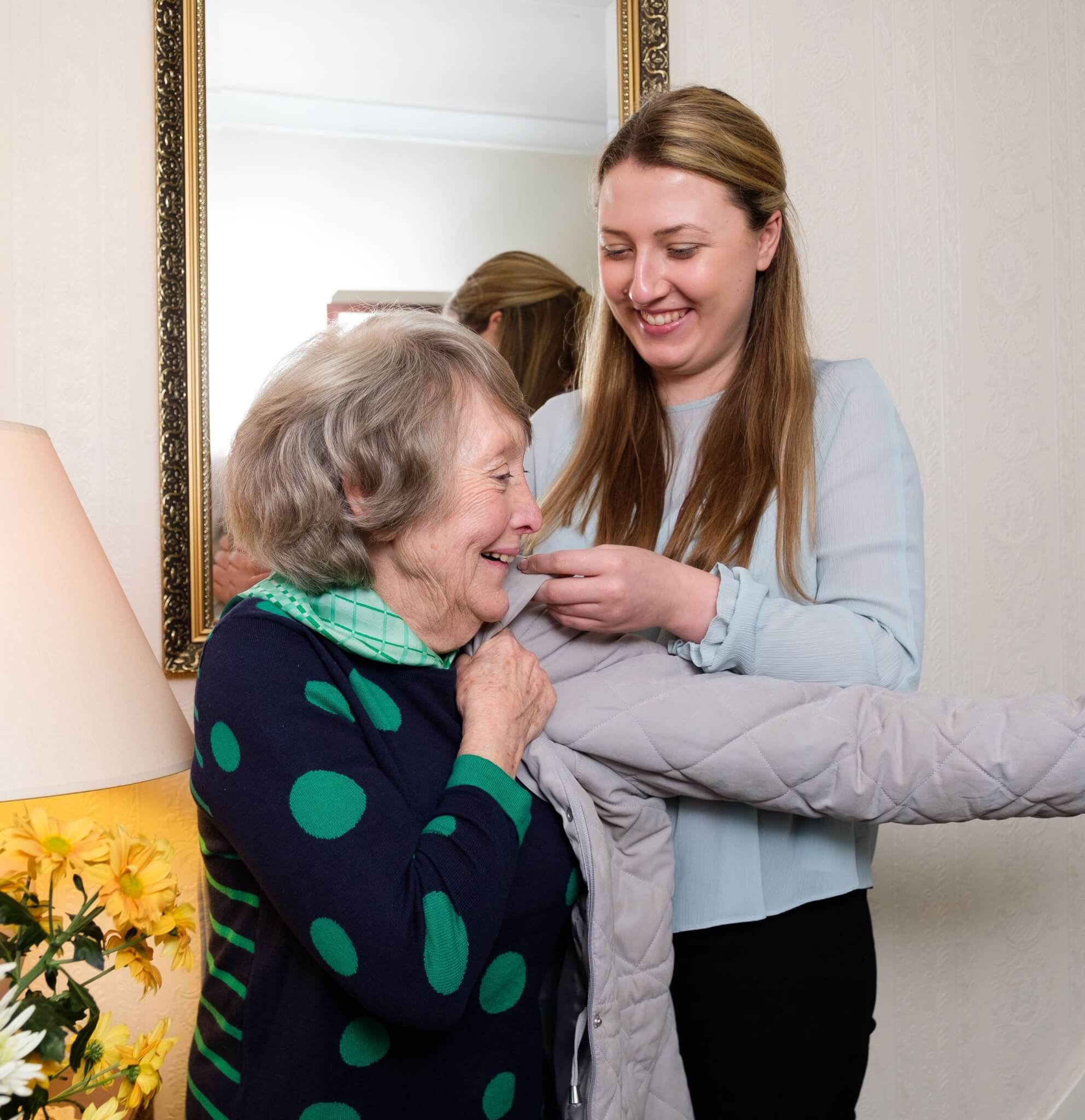 Home Instead live-in carer helping her client put on her coat