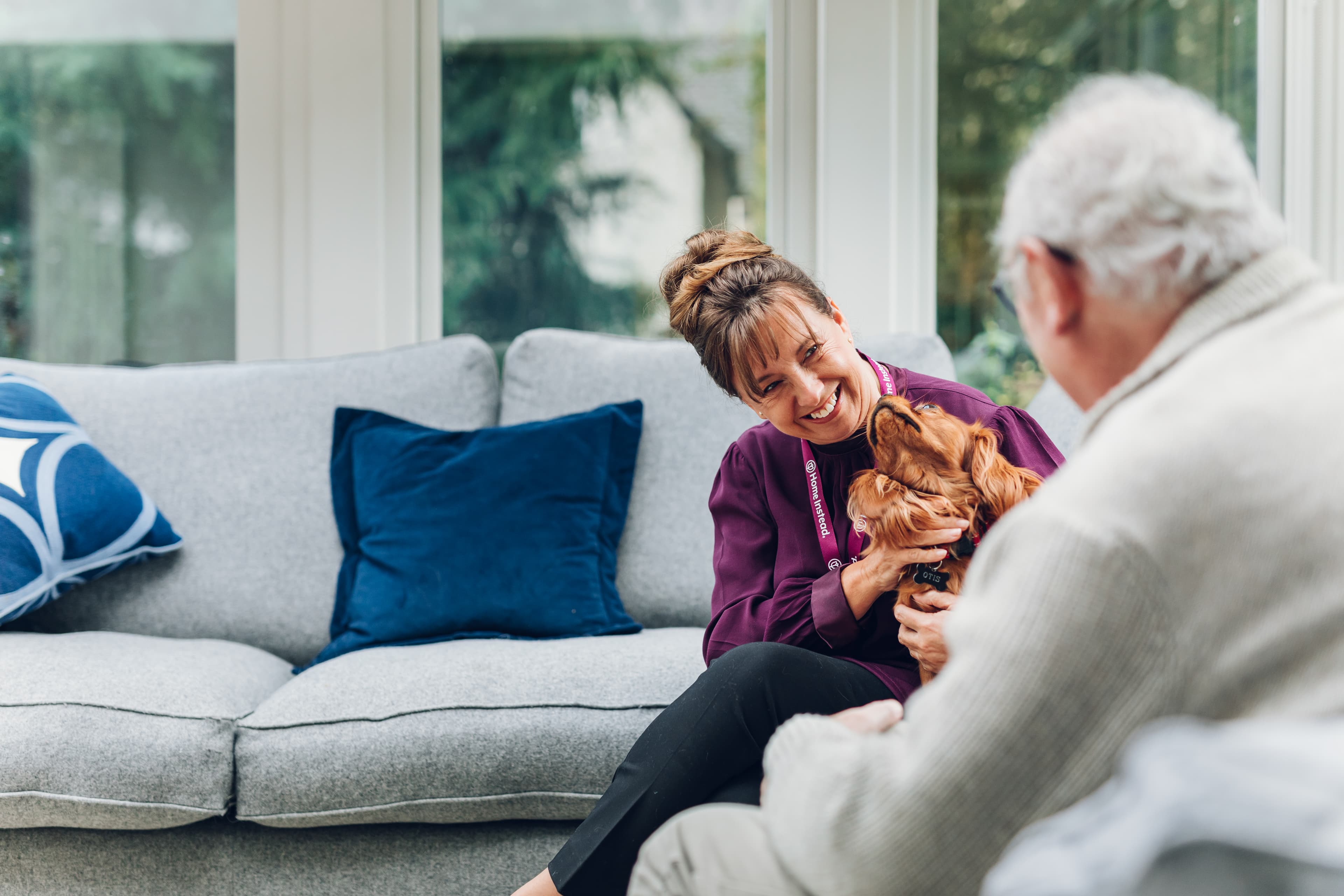 Female Care Professional with male client on companionship visit, petting dog