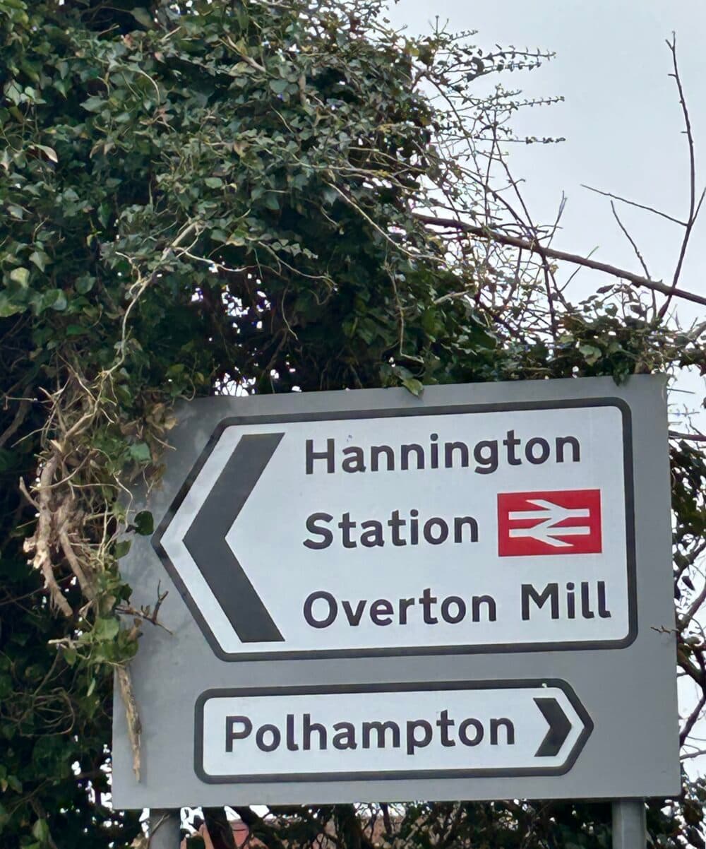 Street sign in Overton pointing to Hannington, the Station and Overton Mill in one direction and Polhampton in the other.