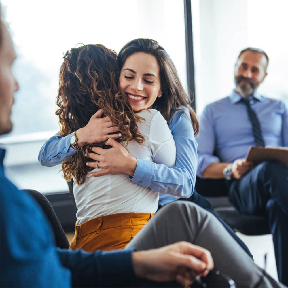 two ladies hugging at a support group meeting