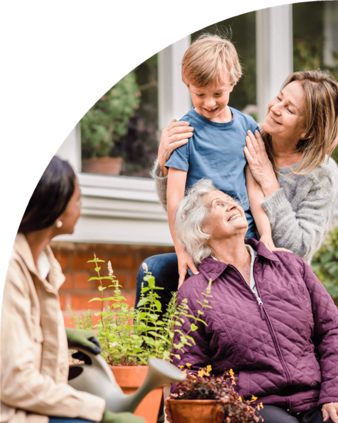 Three generations enjoying each other's company in a cozy outdoor garden setting. - Home Instead