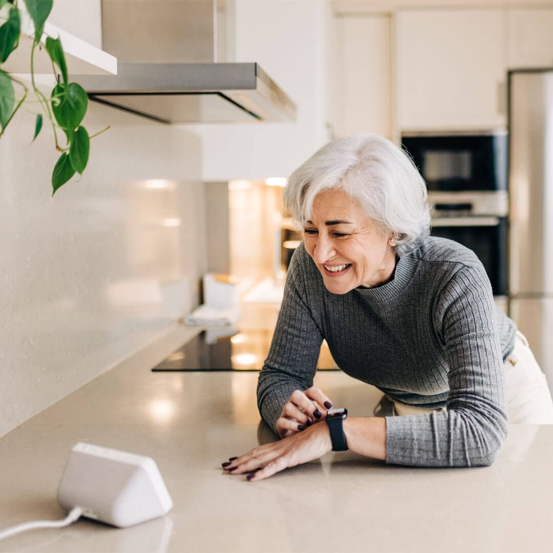 lady talking to a smart speaker in her kitchen