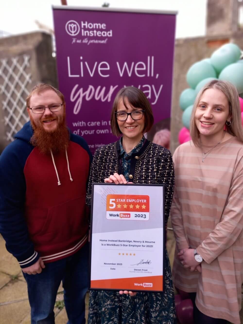 Three people in front of a "Home Instead" banner holding a sign that says "5 Star Employer 2023. - Home Instead