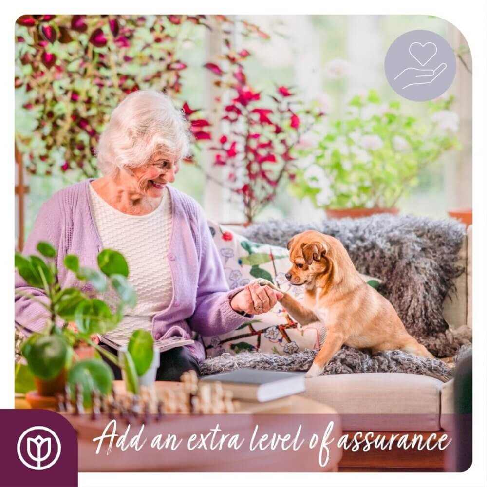 An elderly woman smiling at a small dog sitting on a couch, with text overlay "Add an extra level of assurance. - Home Instead