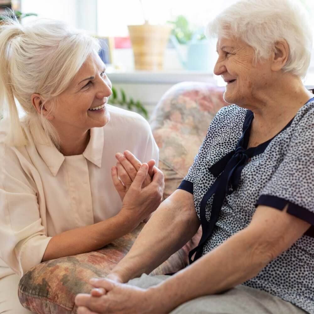 Daughter kneeling, talking to Mum sat on chair beside her