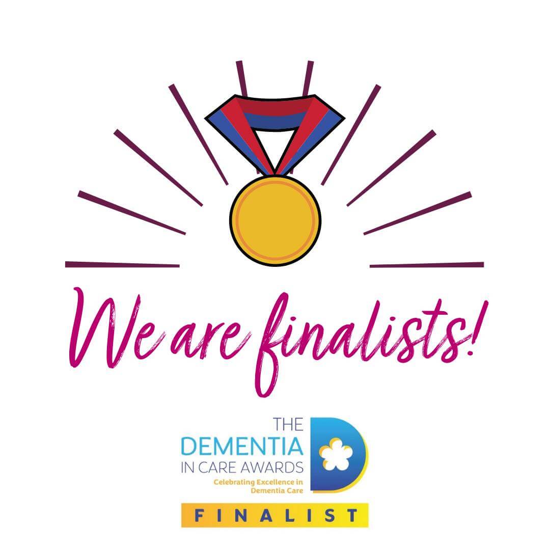 A gold medal with rays and text reading "We are finalists!" for the Dementia in Care Awards. - Home Instead