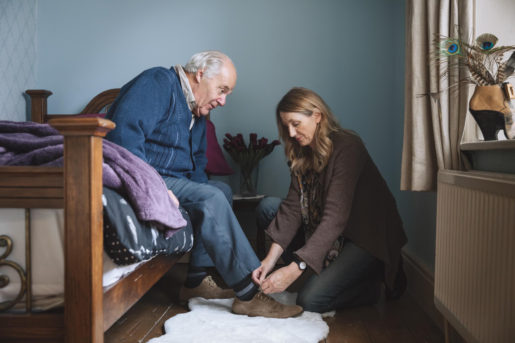 Carer helps frail man to put his shoes on