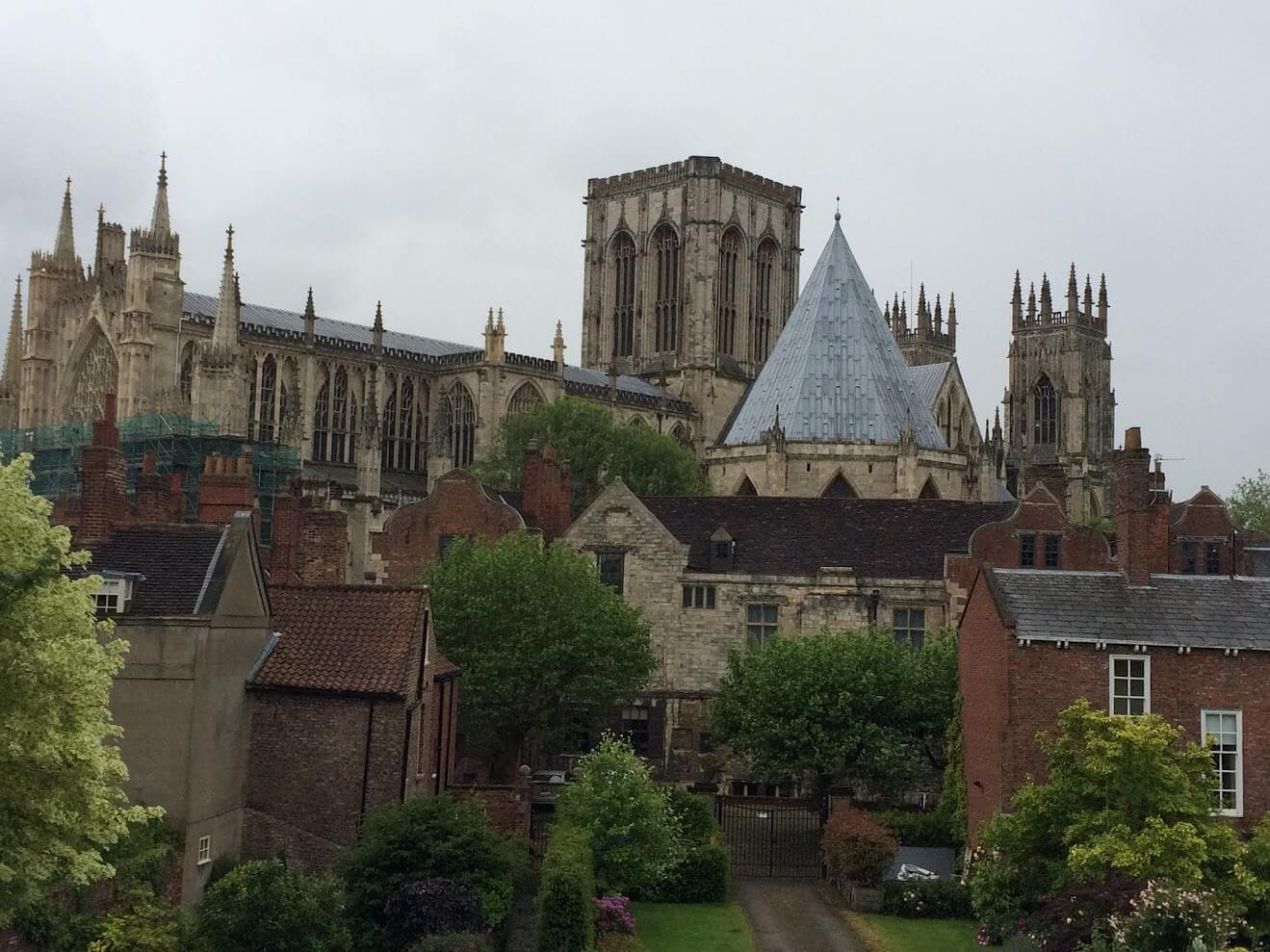 View of York Minster, featuring Gothic architecture and surrounding buildings, trees, and cloudy sky. - Home Instead