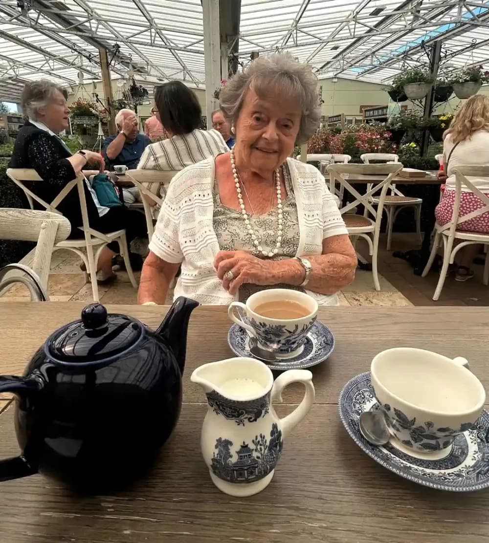 Home Instead Fleet client Ivy enjoying a pot of tea at her local garden centre
