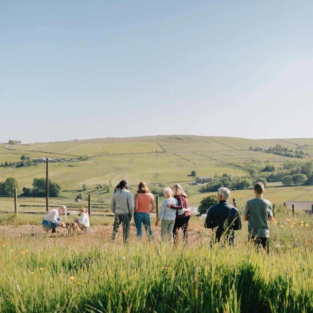 A group of people standing in a field looking at the landscape under a clear blue sky. - Home Instead
