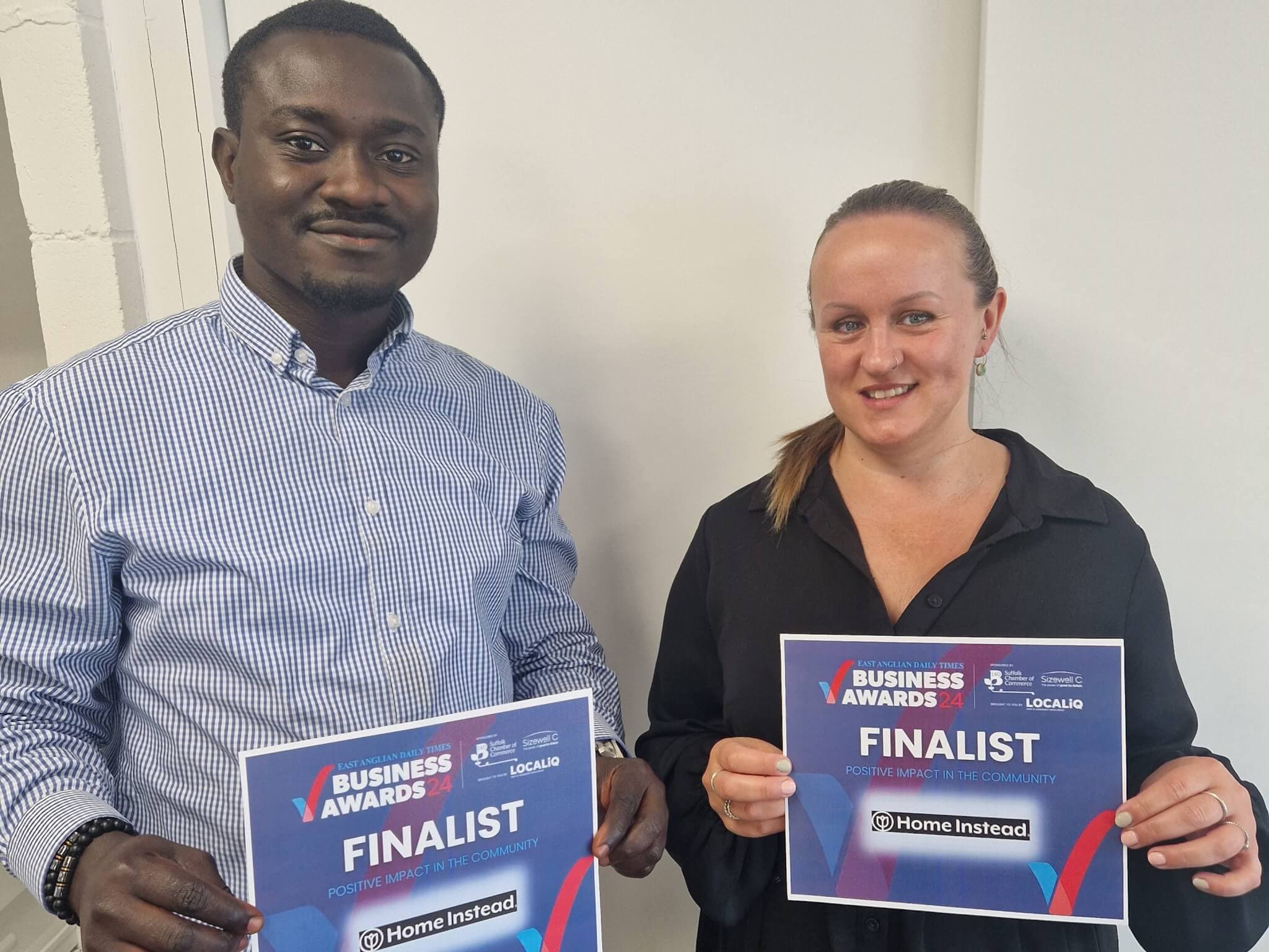 colleagues holding certificates that say "Business Awards Finalist" and smiling at the camera. - Home Instead