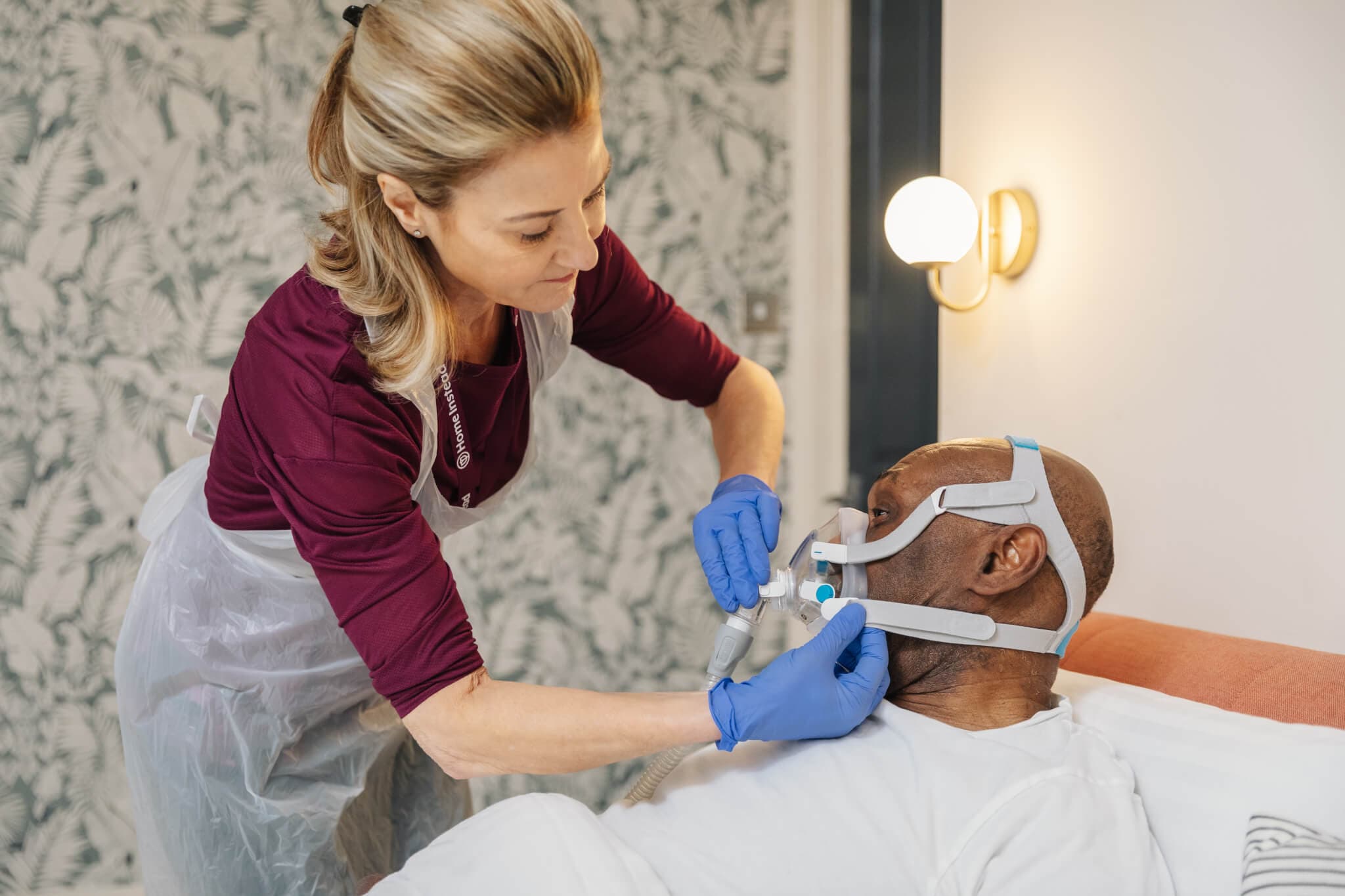 Female Home Instead Care Professional assisting male client with ventilation.