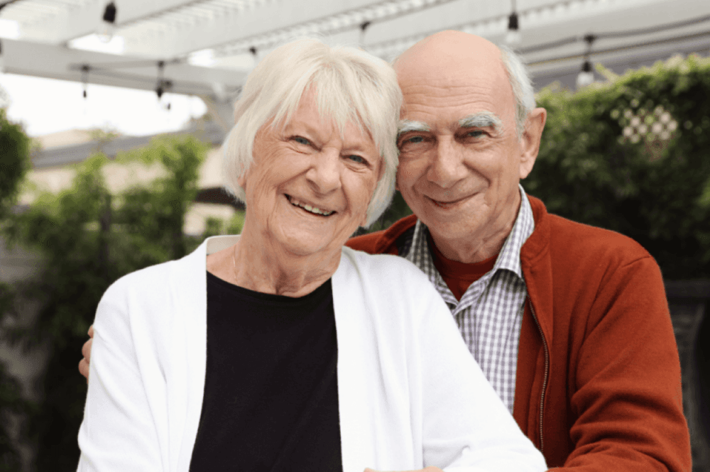 Elderly couple smiling and looking happy in their garden