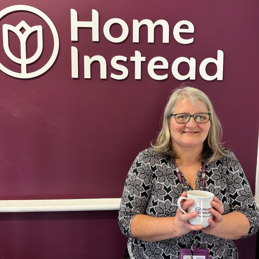 Our Care Professional/Live in Care Team Leader Ruth, holding a coffee and smiling