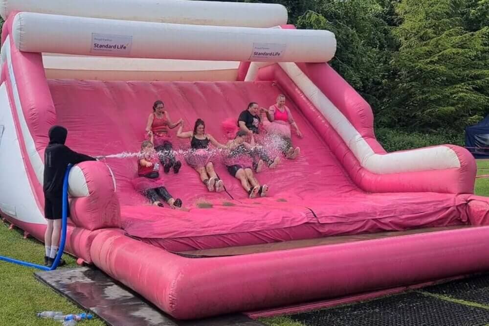 Participants in "Race For Life Pretty Muddy" on a pink inflatable slide