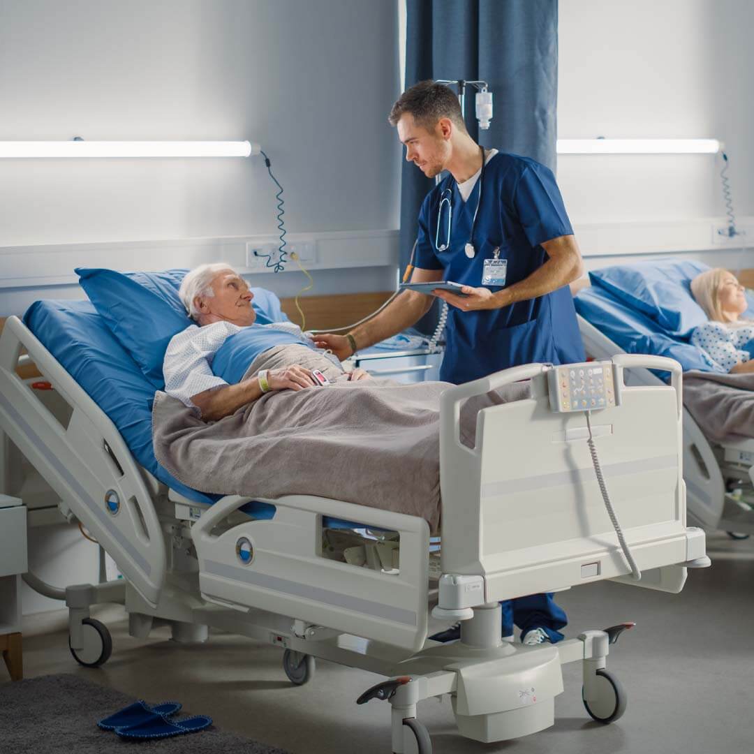 older man lying in a hospital bed being seen by a doctor