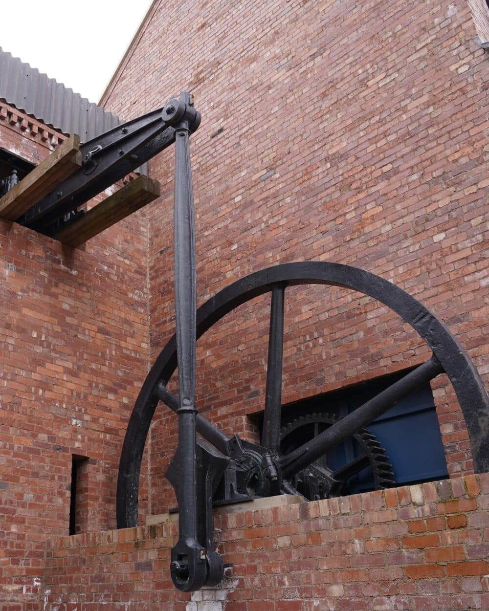 Large industrial gear and beam mechanism attached to an old brick building. - Home Instead