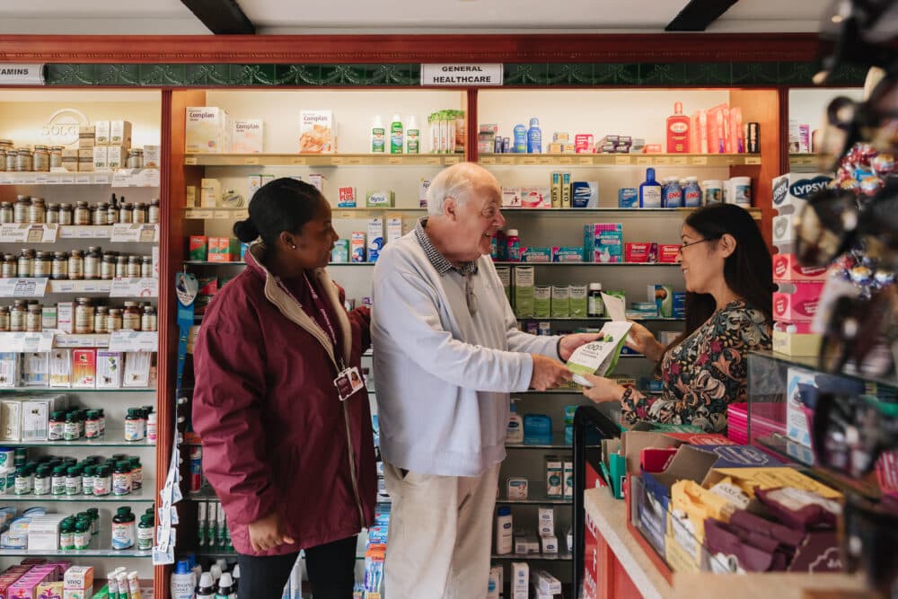Female Home Instead Care Pro helps a male client to pick up his pharmacy prescription